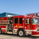 Vibrant red fire truck from Asheville Fire Department parked outside Petco on a sunny day.